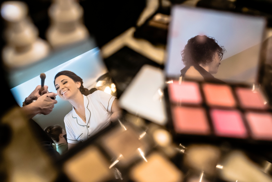 A reflection of a bride getting her makeup done before her wedding.